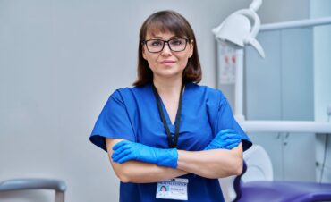 Portrait of female doctor dentist in office. Confident middle aged woman looking at camera with crossed arms near dental chair. Dentistry, medicine, specialist, career, dental health care concept